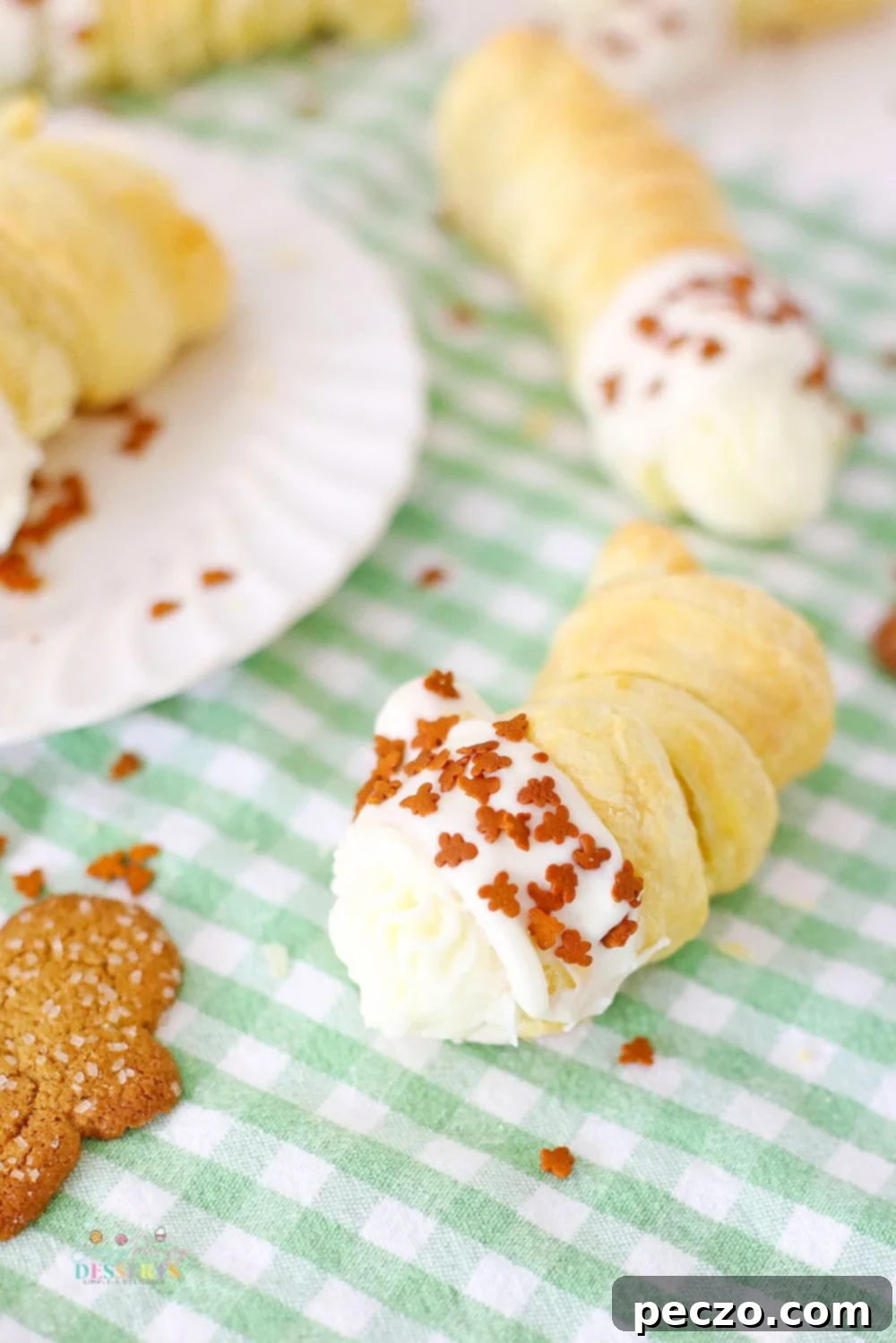 Close-up of a single gingerbread cream horn, showcasing the golden, flaky pastry and the rich cream filling with gingerbread sprinkles.
