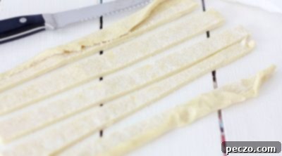 Puff pastry being rolled and cut into strips for cream horns.