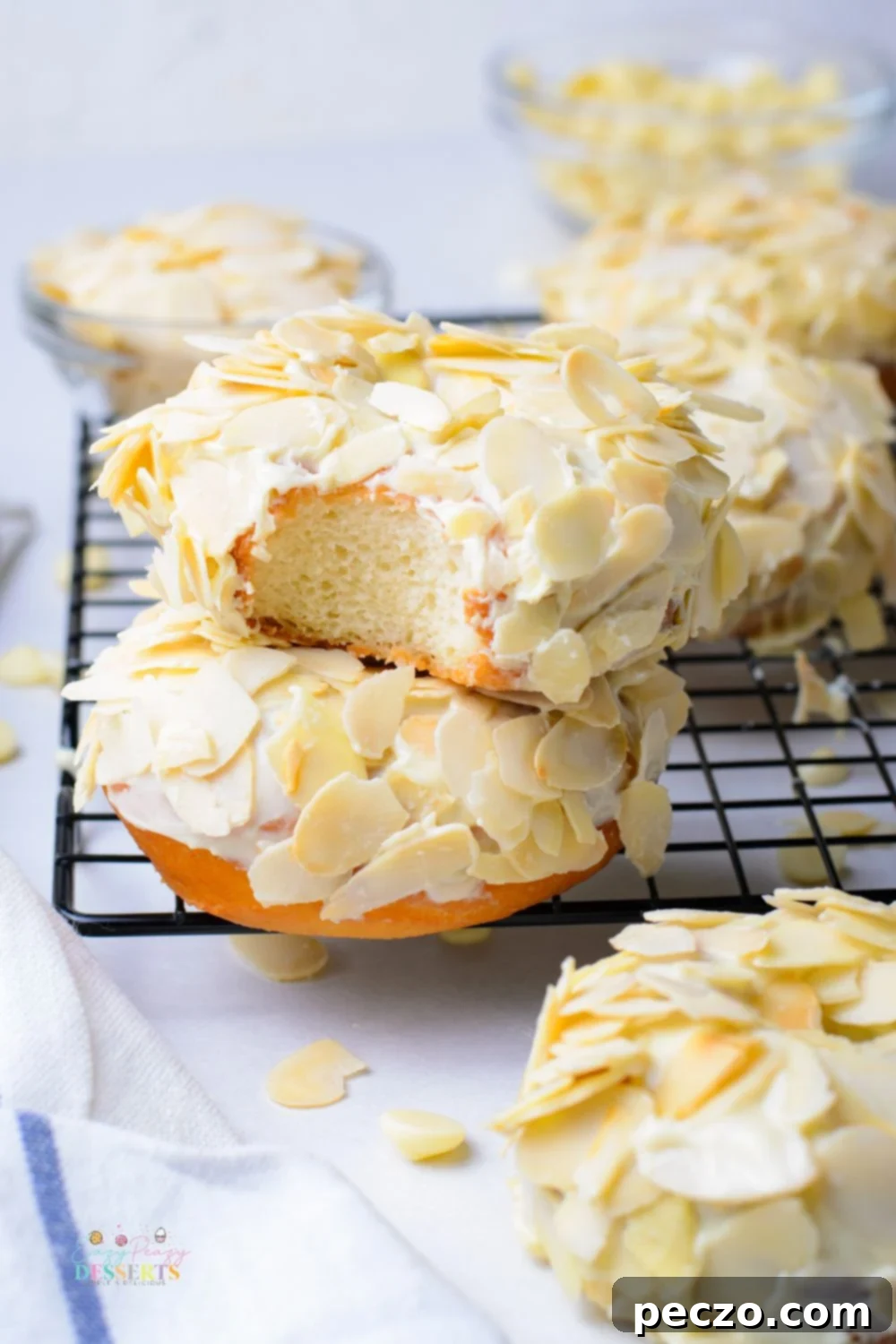 Image of two raised donuts covered in white chocolate glaze and shaved almonds