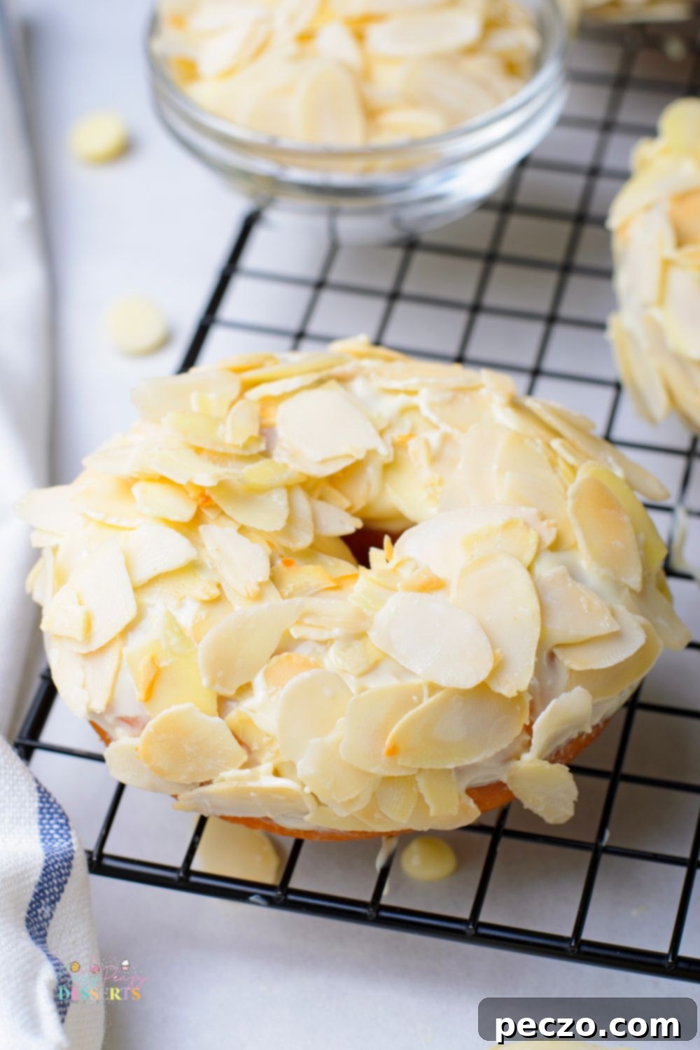 Close up image of yeast donut covered in white chocolate glaze and shaved almonds