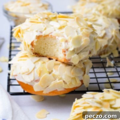 Pillowy Soft Yeast Donuts 7 Image of two raised donuts covered in white chocolate glaze and shaved almonds