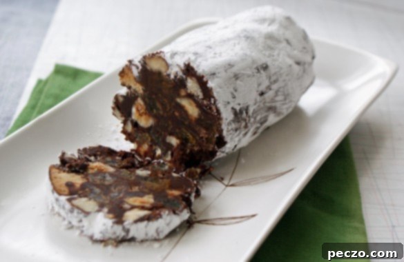 Chocolate Biscuit Log 2 Delicious slices of homemade chocolate salami, showcasing the rich chocolate base studded with crumbled cookies, toasted hazelnuts, and golden raisins.