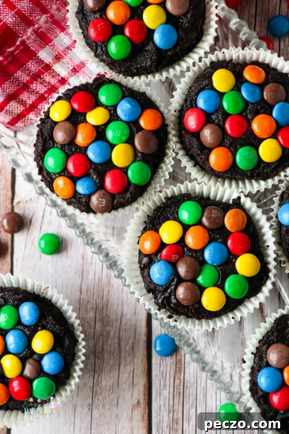 Overhead view of several chocolate cupcakes with colorful M&M's and creamy frosting