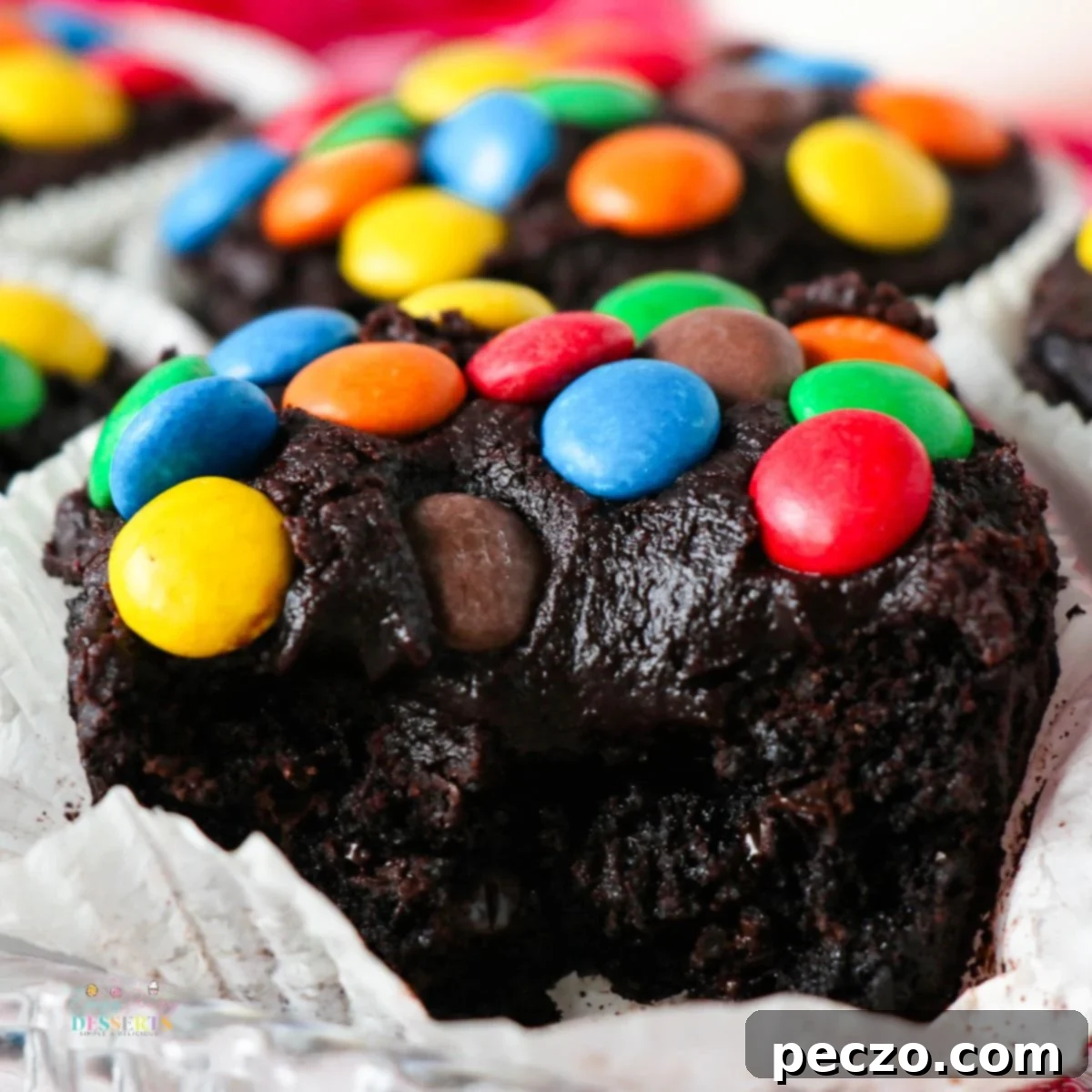 Close-up image of rich chocolate brownie cupcakes with smooth chocolate frosting and colorful M&M candies