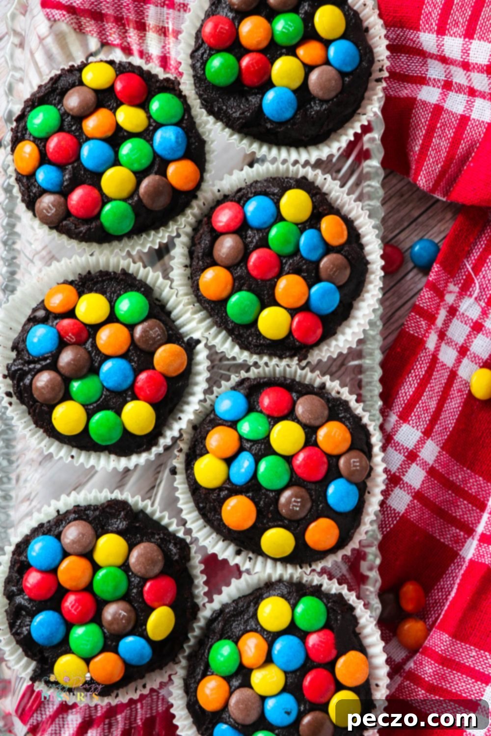 Overhead shot of several chocolate frosting cupcakes adorned with vibrant M&M's, ready to be enjoyed