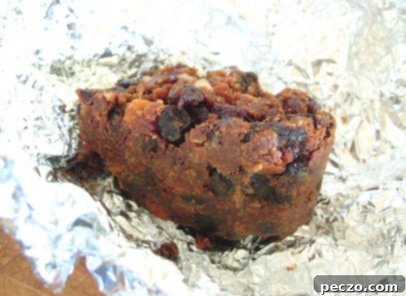 Rich, dense slice of dark fruitcake with dried fruits and nuts, perfectly aged and ready to be enjoyed.