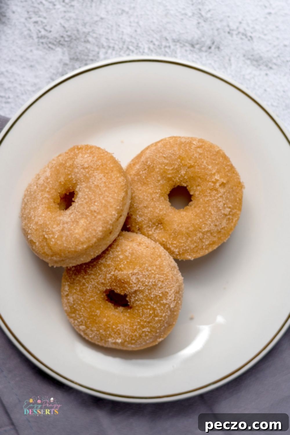 Image of three vegan cinnamon donuts on a desserts plate
