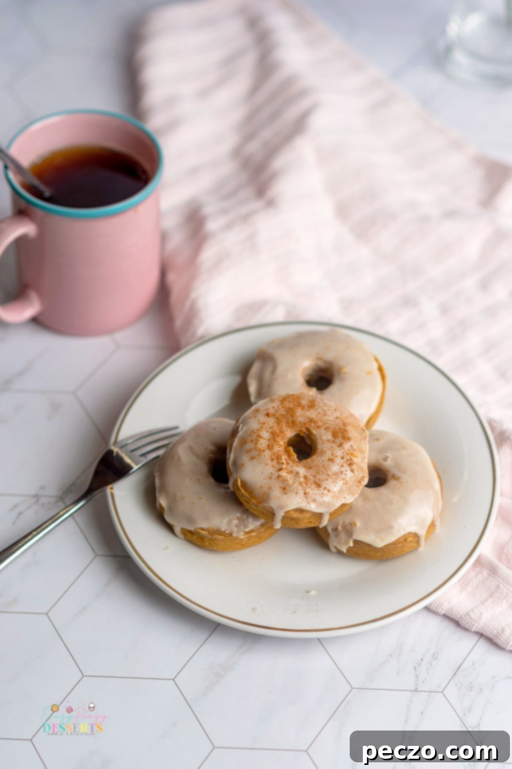 A charming close-up of four delicious vegan pumpkin donuts adorned with glistening maple glaze, presented on a rustic wooden serving plate.