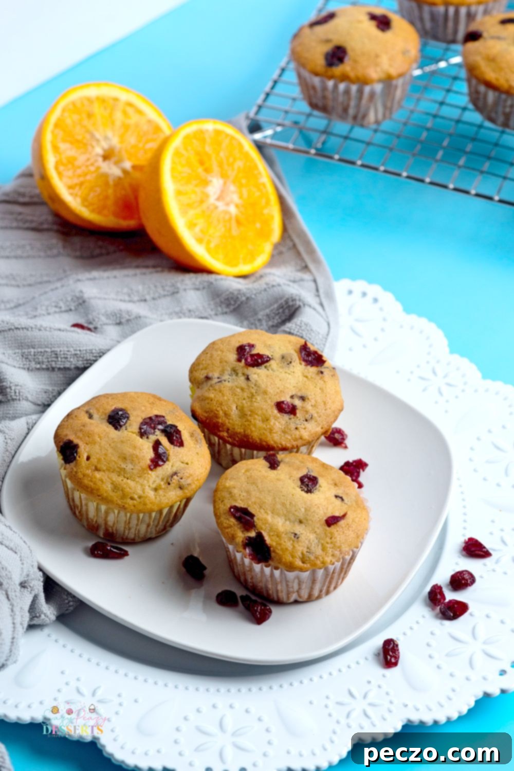 Sweet & Tart Vegan Orange Cranberry Muffins 3 Three healthy cranberry orange muffins on a white serving plate