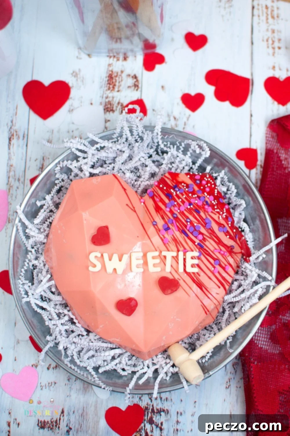 Over head image of breakable chocolate heart for Valentine's day, with a small mallet beside it.