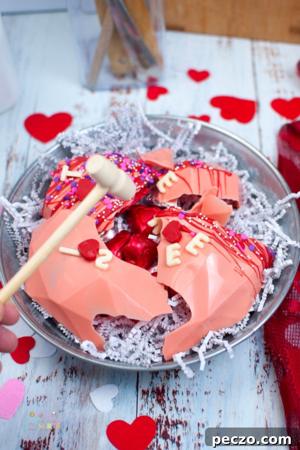 Image of a pink breakable heart made with chocolate, adorned with sprinkles and a personalized message.