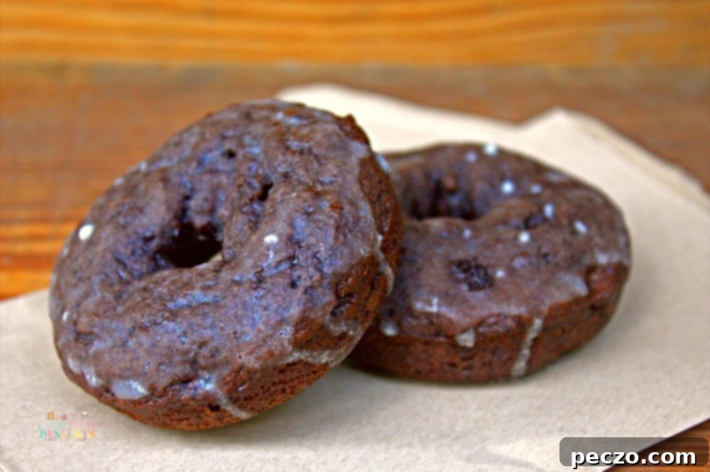 Image of a couple of glazed chocolate donuts on baking paper
