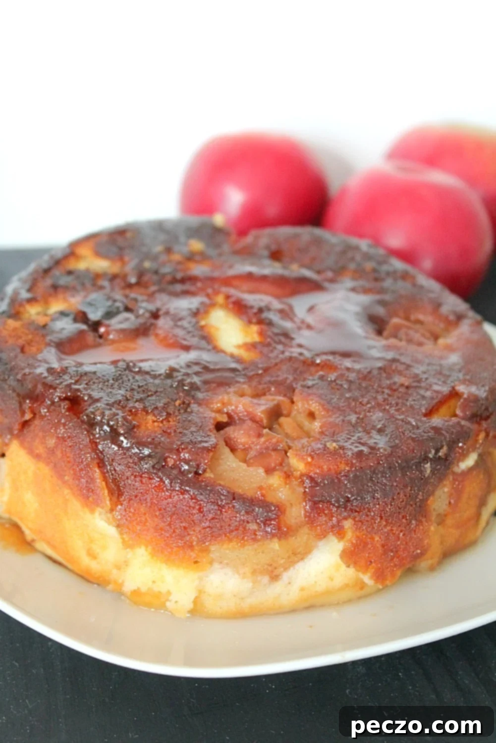 Close up image of apple upside down cake on a plate, showcasing the caramel and apple topping