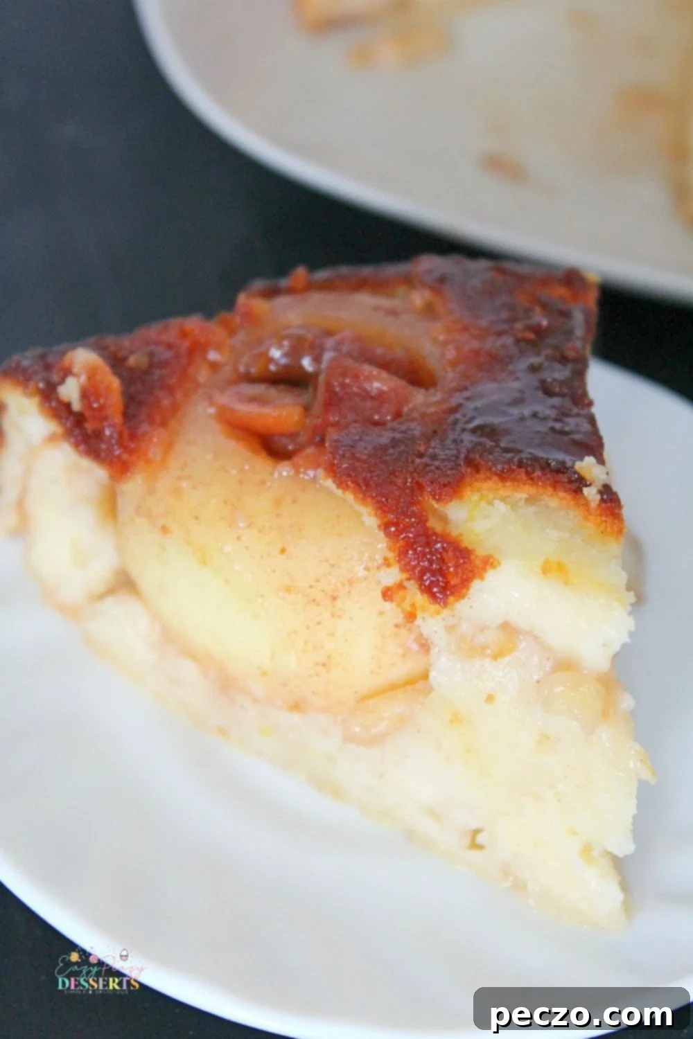 Close up image of a slice of apple turnover cake, showing the caramel and jam filling