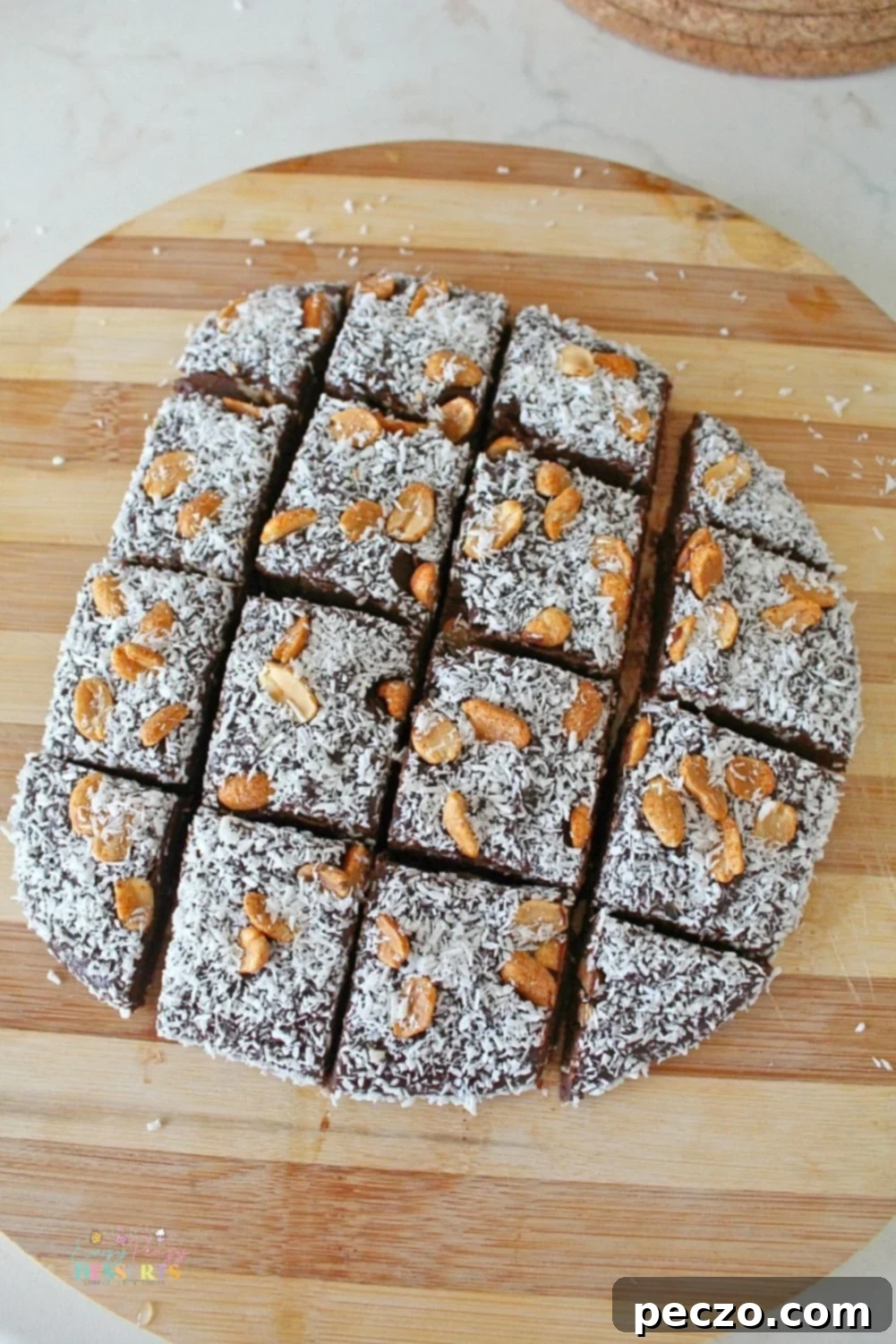 Overhead view of homemade microwave chocolate fudge, beautifully decorated with a generous sprinkle of white coconut flakes and chopped peanuts, ready to be sliced