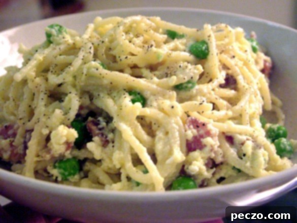 Delicious Spaghetti Carbonara with vibrant green peas, ready to serve in a bowl.