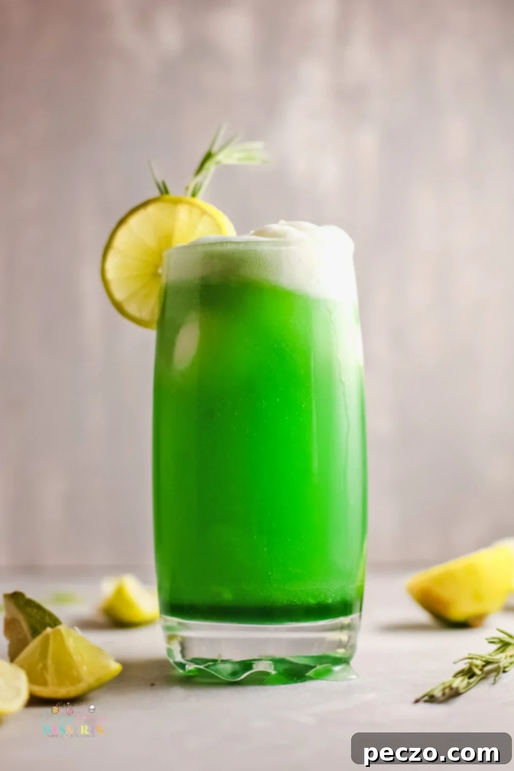 A tall glass filled with bright green St. Patrick's Day lime sherbet punch, garnished with lime slices and a sprig of rosemary.