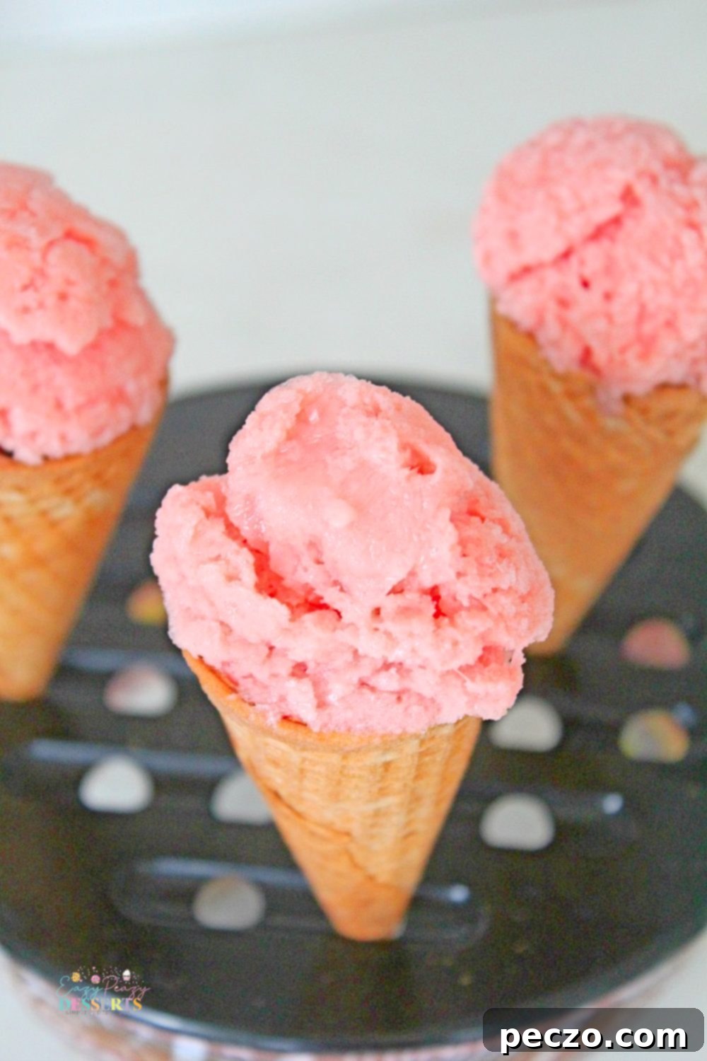 Creamy watermelon ice cream in ice cream cones, garnished with fresh mint