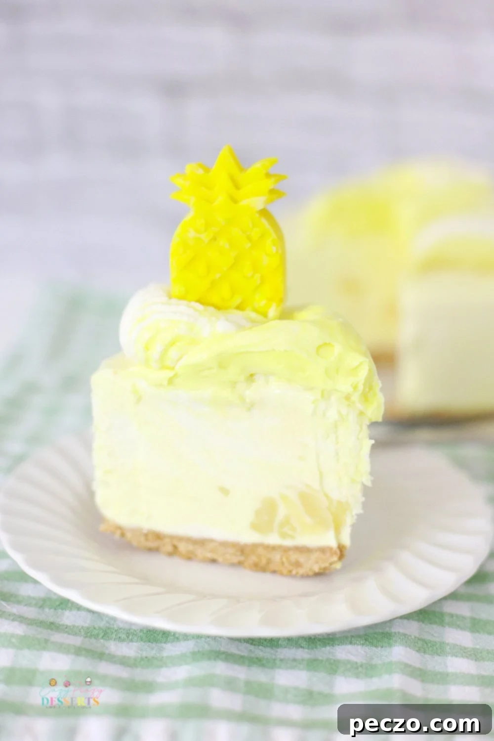 A perfectly sliced no-bake pineapple cheesecake on a white dessert plate, garnished with fresh pineapple and whipped cream.