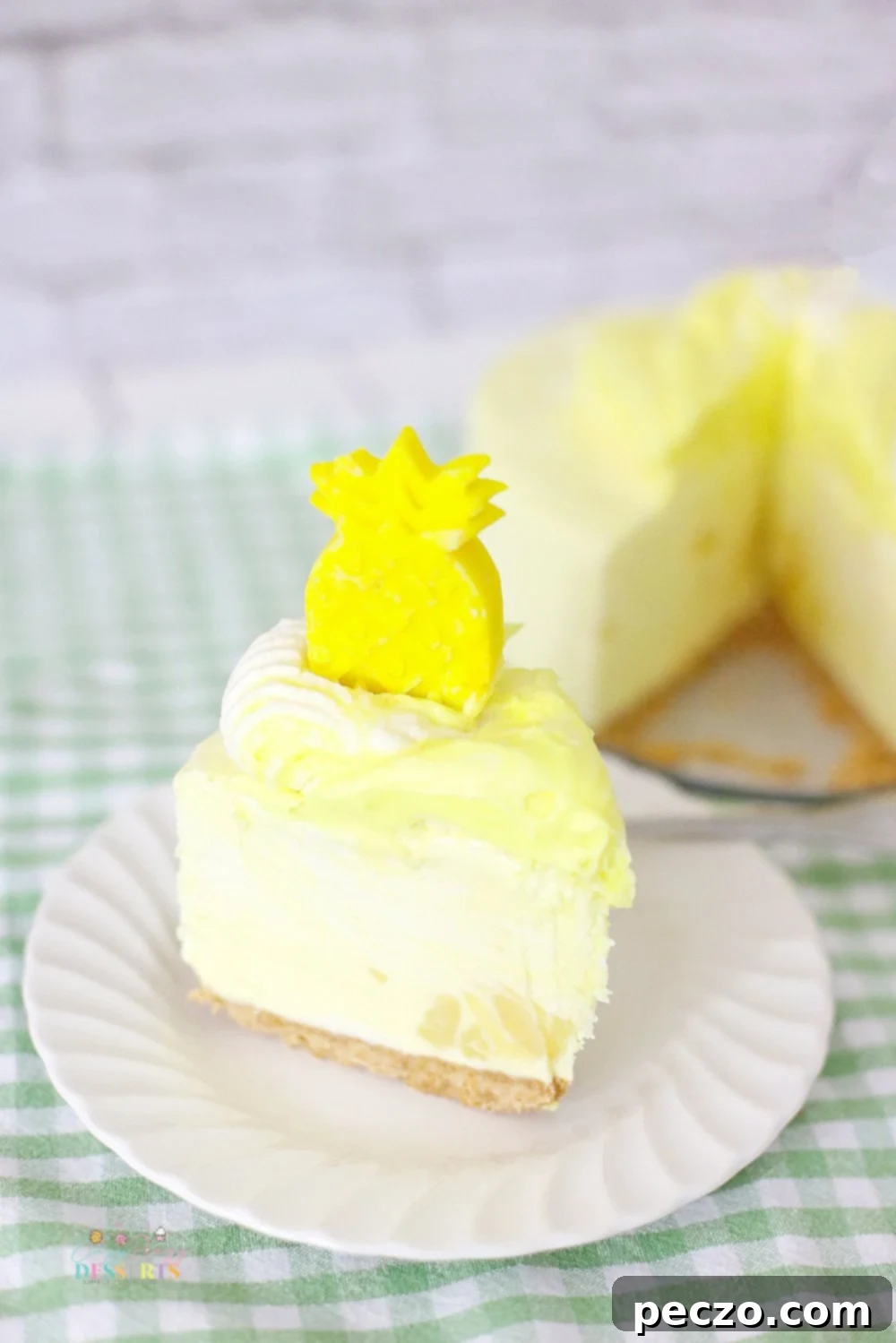 A slice of pineapple whip cheesecake, garnished with a chocolate pineapple and a dollop of whipped cream.