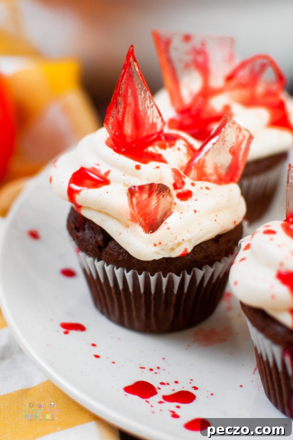 Close up image of bloody cupcakes with sugar glass shards and fake blood, highlighting the glossy texture of the edible glass.