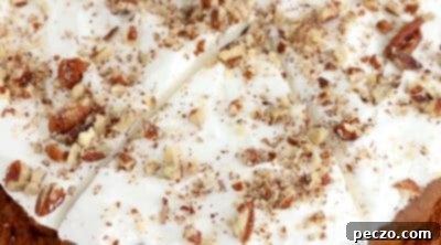 Decorating cooled air fryer pumpkin cake with Cool Whip and pecans