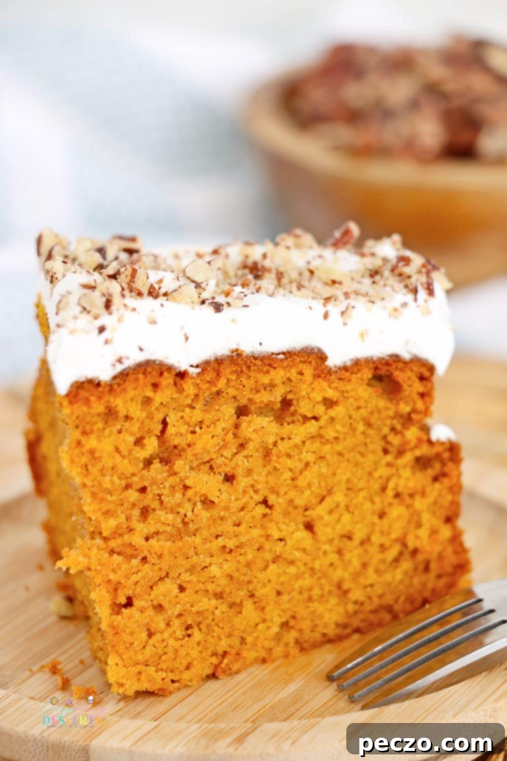 A slice of air fryer pumpkin cake with a light frosting and chopped nuts