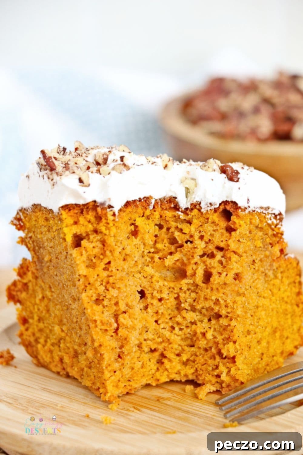 Air fryer pumpkin cake with a generous layer of Cool Whip and chopped pecans