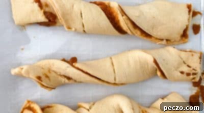 Twisting pumpkin pastry strips and pinching the ends before baking.
