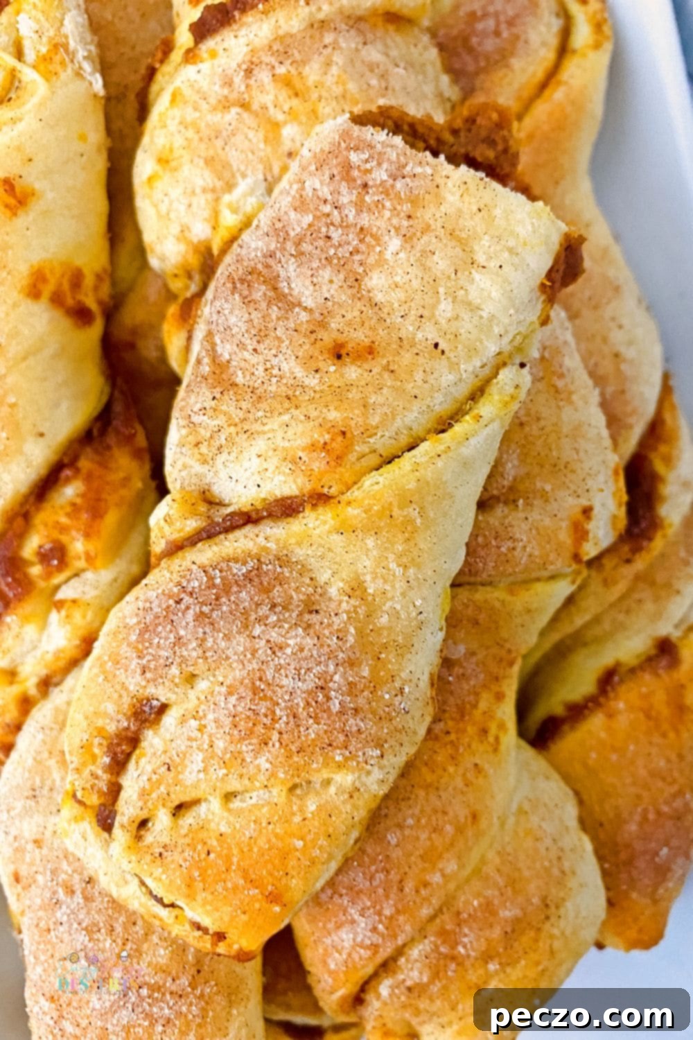 Close up image of golden brown pumpkin pastries twisted into appealing strips, showcasing their texture.