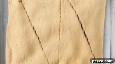 Spreading pumpkin filling over crescent roll dough and topping with another layer.