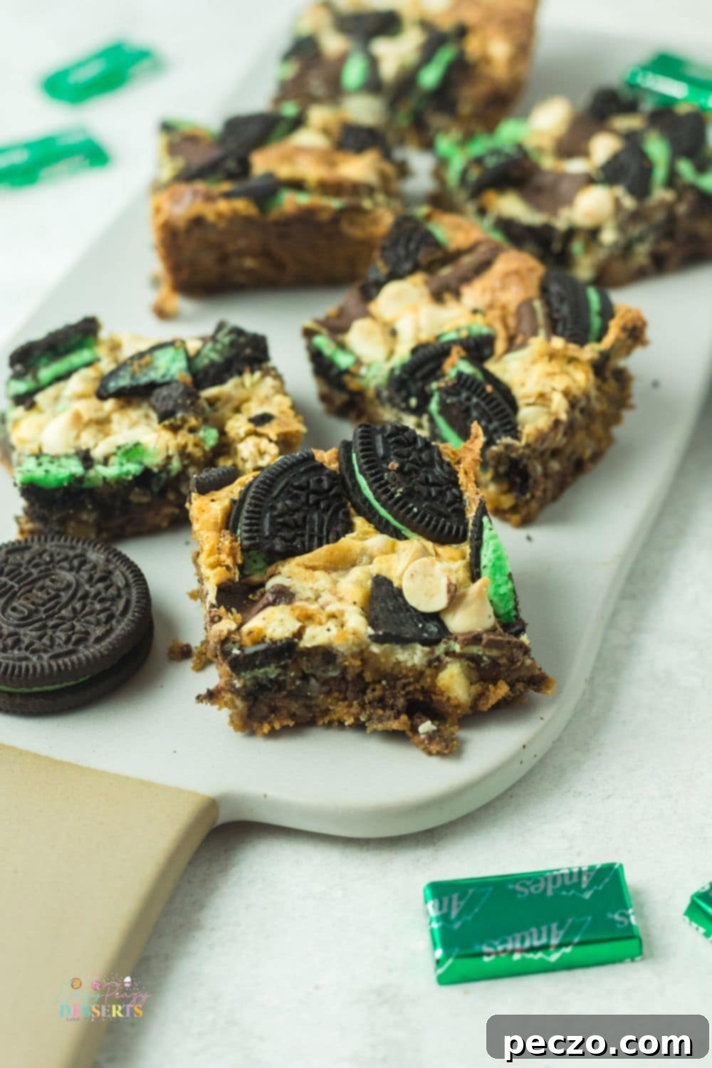 Image of mint cookie bars on a white serving plate with Andes mints and mint Oreo cookies on a side