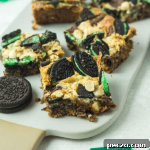 Image of mint cookie bars on a white serving plate with Andes mints and mint Oreo cookies on a side