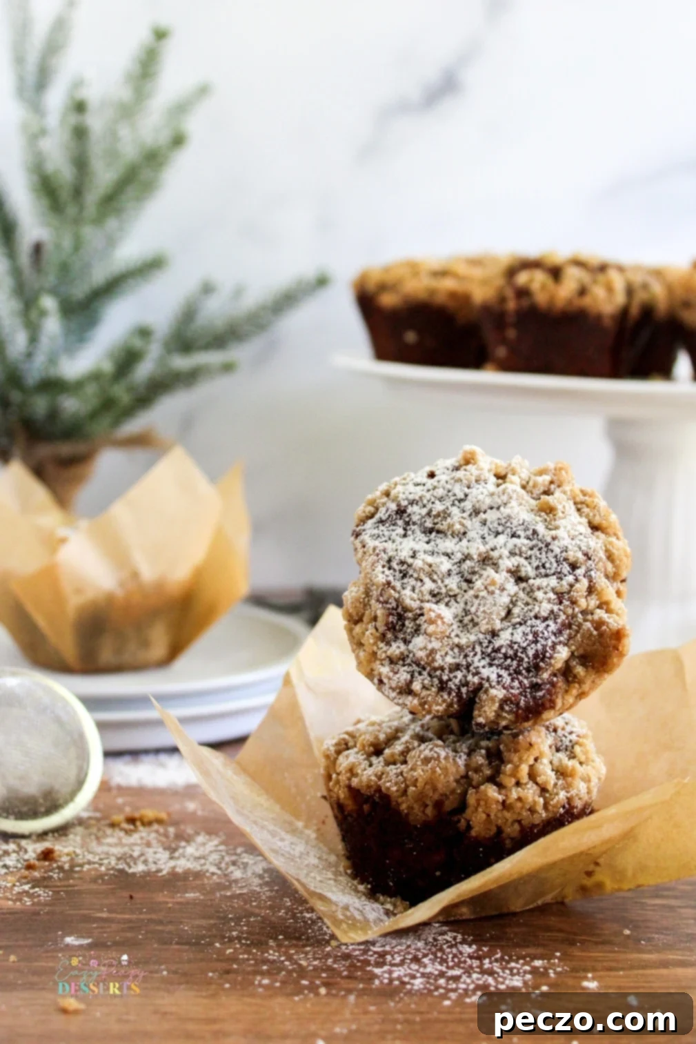 Two perfectly golden gingerbread muffins with a generous streusel topping, ready for the holidays