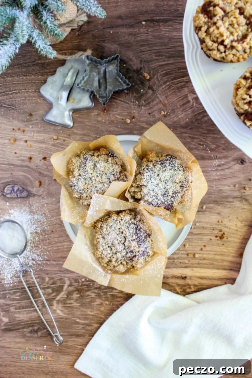 Overhead view of several gingerbread streusel muffins, artfully arranged with fresh ginger slices for a festive holiday feel