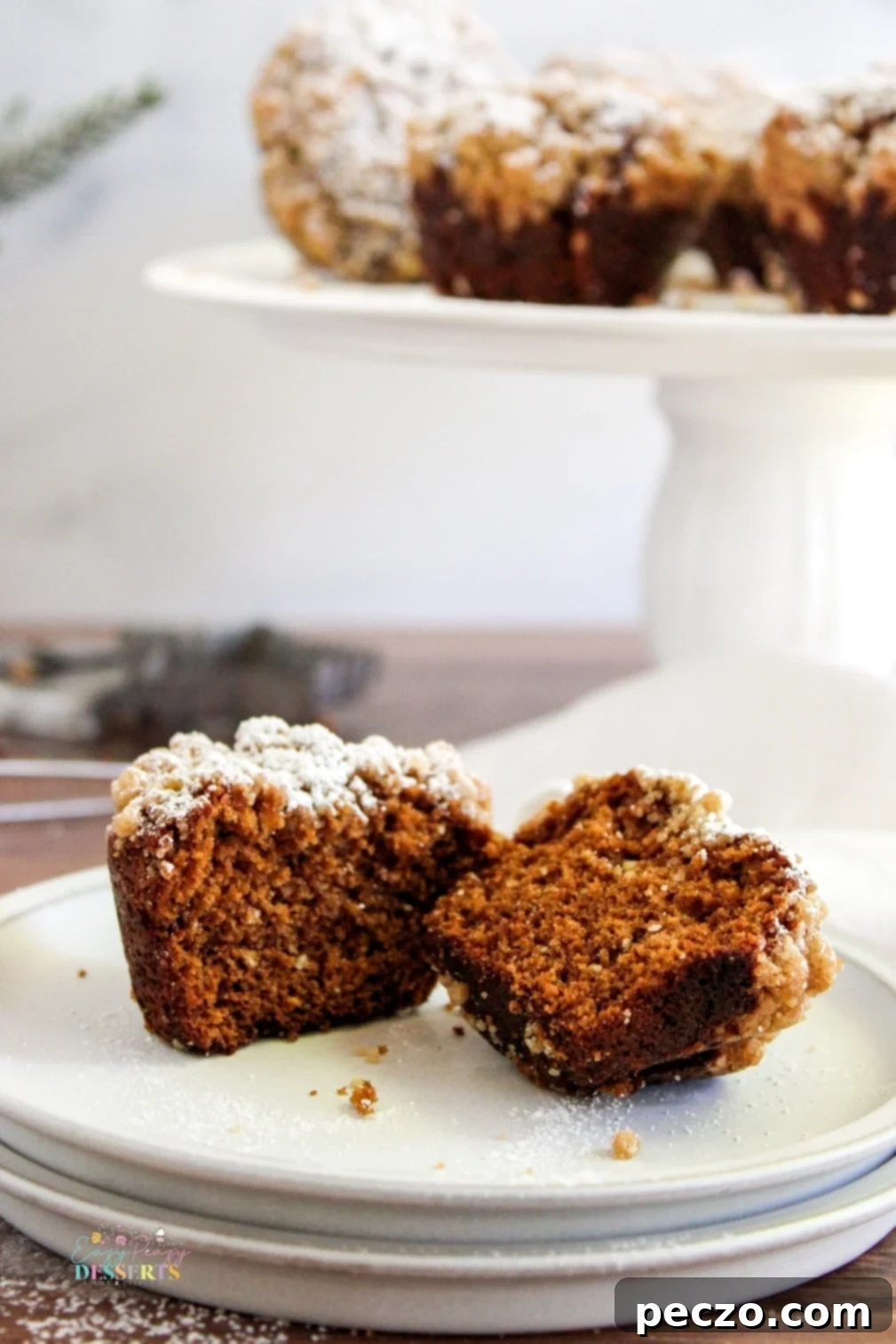 A gingerbread streusel muffin cut in half, showcasing its tender, moist interior and golden crumb, along with the streusel topping