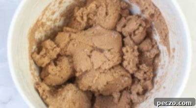 Gradually mixing dry and wet ingredients to form hot cocoa cookie dough