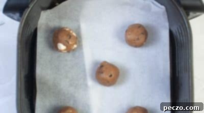 Scooping and placing hot cocoa cookie dough balls in an air fryer basket