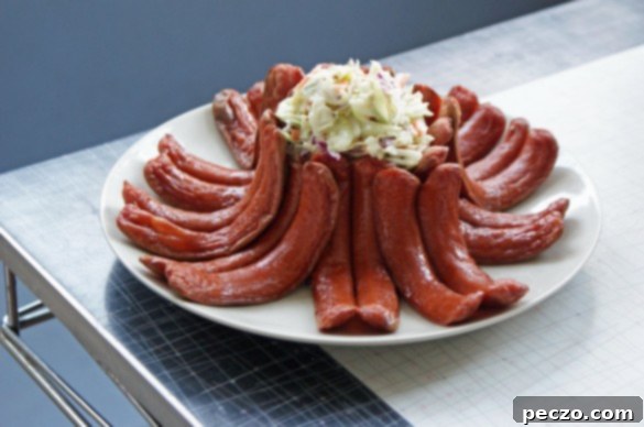A perfectly assembled Crown Rack of Hot Dogs, with hot dogs curled to form a circle around a mound of creamy coleslaw, showcasing a whimsical retro dish.