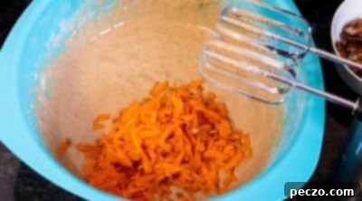 Grated carrots being folded into the donut batter.
