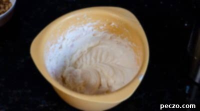 Milk being added slowly to cream cheese frosting.