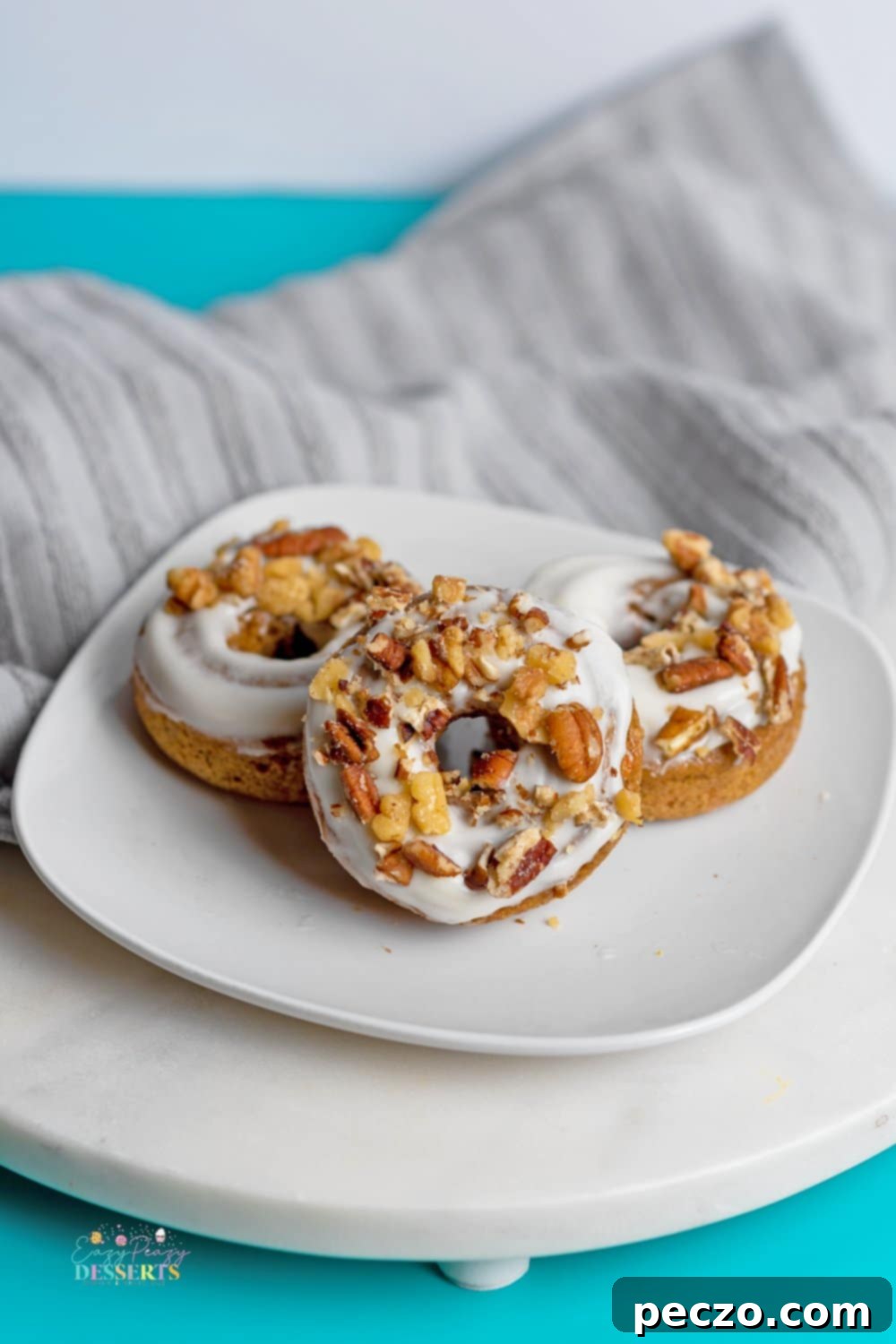 Freshly baked carrot cake donuts cooling on a wire rack, ready for frosting.