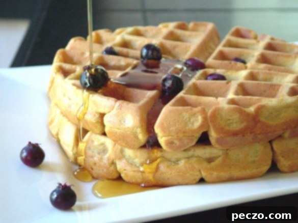 Delicious homemade pumpkin waffles drizzled with pure maple syrup, served warm for breakfast.