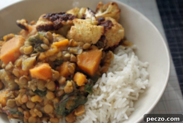 A vibrant bowl of curried lentils and sweet potatoes, garnished with fresh herbs, ready to be served.