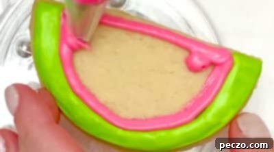 Filling in watermelon cookies with pink icing