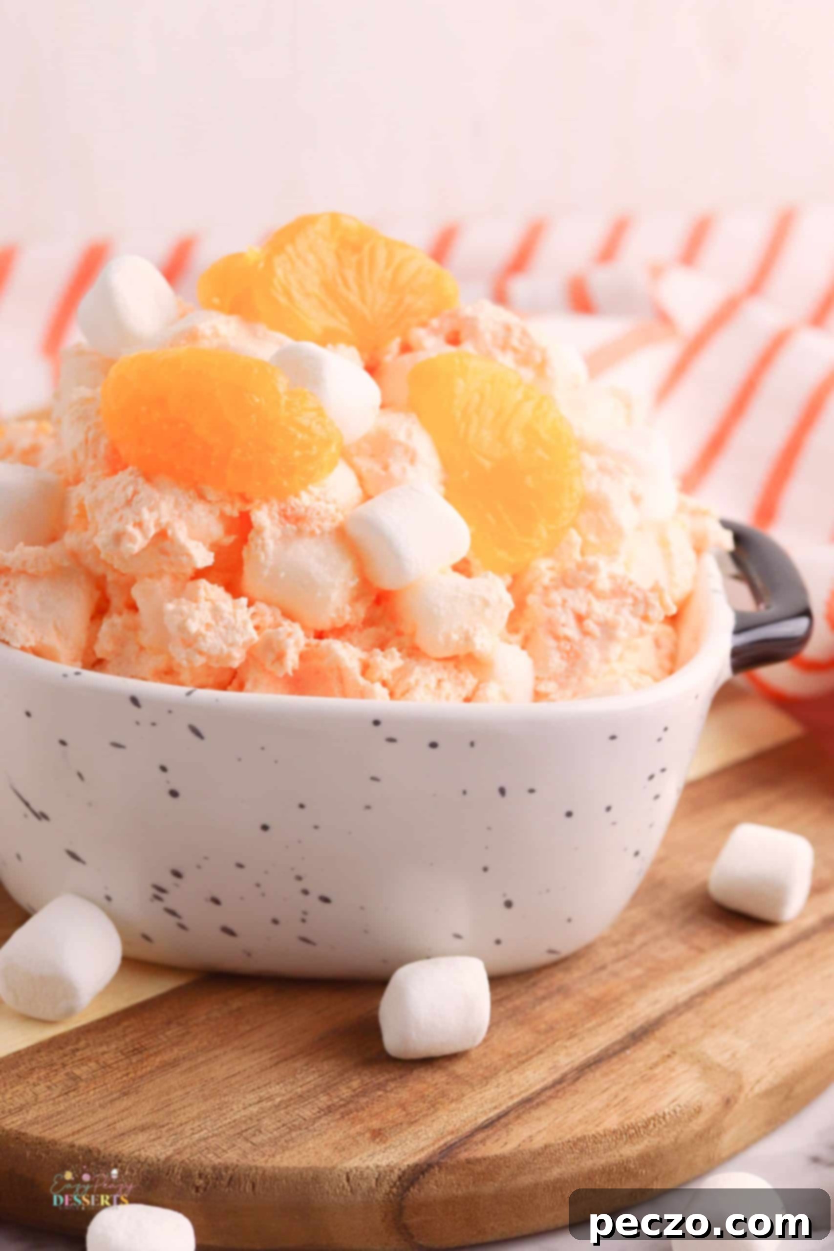Three glass bowls of orange fluff dessert, garnished with orange slices and mint