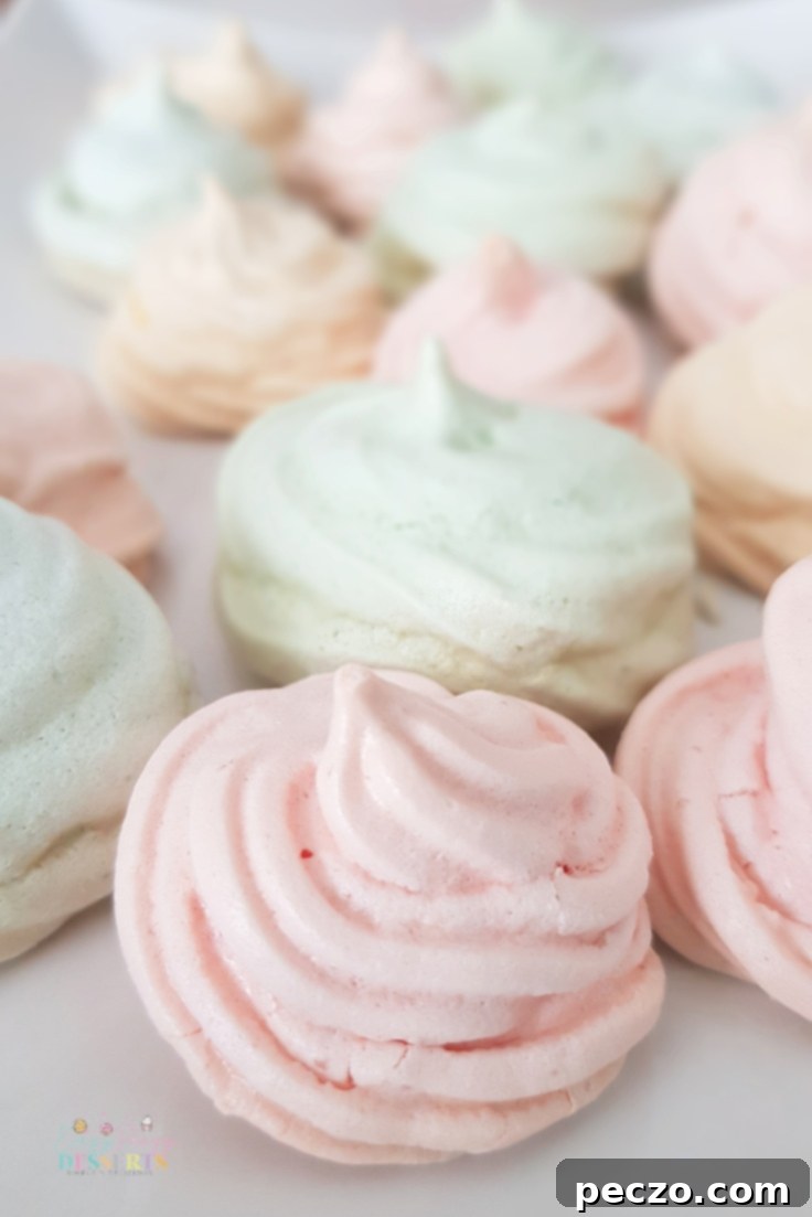 Colorful Meringue cookies arrayed on a white background, showcasing their delicate texture and vibrant hues, perfect for a festive dessert table.