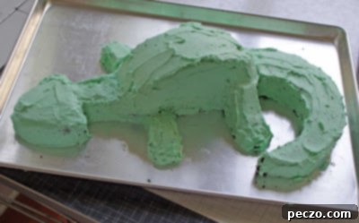 Decorated dragon cake with vibrant green icing, awaiting final embellishments