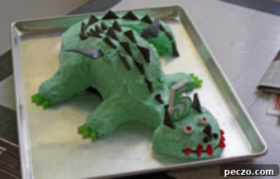 The completed dragon birthday cake, fully decorated with candies and toy wings