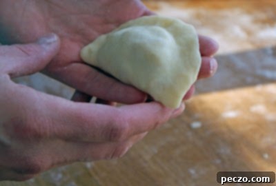 A batch of perfectly formed, uncooked homemade perogies laid out, showcasing the careful craft and inviting promise of traditional Ukrainian cooking.